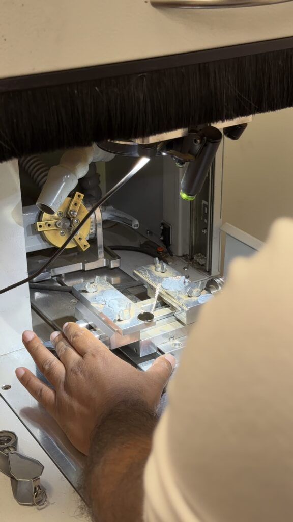 A workshop operator working at an enclosed machine with a clamped piece